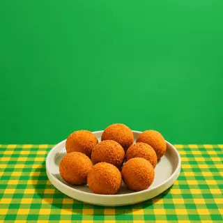 Eight golden-brown fried cheese balls are served on a white plate over a green and yellow checkered tablecloth against a solid green background.