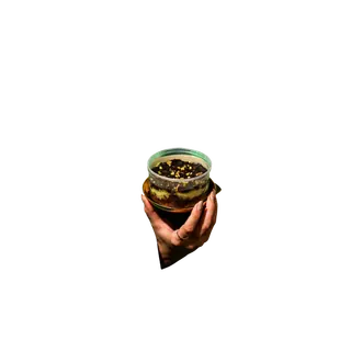 A hand holding a layered chocolate dessert in a clear plastic container against a plain grey background.
