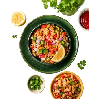 A top-down view of peanut chaat served in bowls with lemon slices, chopped chilies, and coriander leaves on a solid grey background.